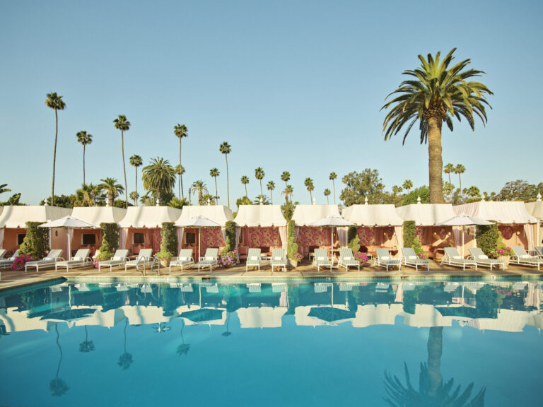 Piscine et cabanas du Beverly Hills Hotel à Los Angeles, avec palmiers, transats et décor rose et vert.
