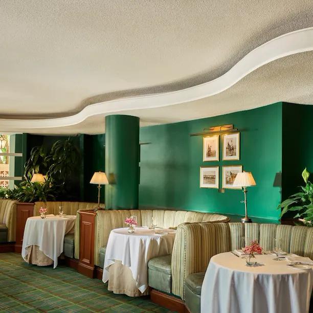 Intérieur du Polo Lounge au Beverly Hills Hotel, avec banquettes vertes, tables nappées et ambiance Old Hollywood.