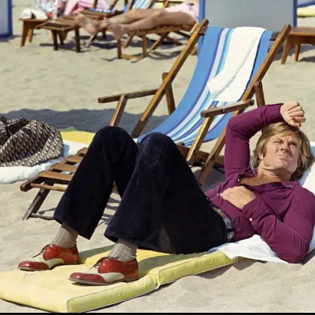 Robert Redford à Cannes, allongé sur un matelas, chemise violine et spectator shoes.