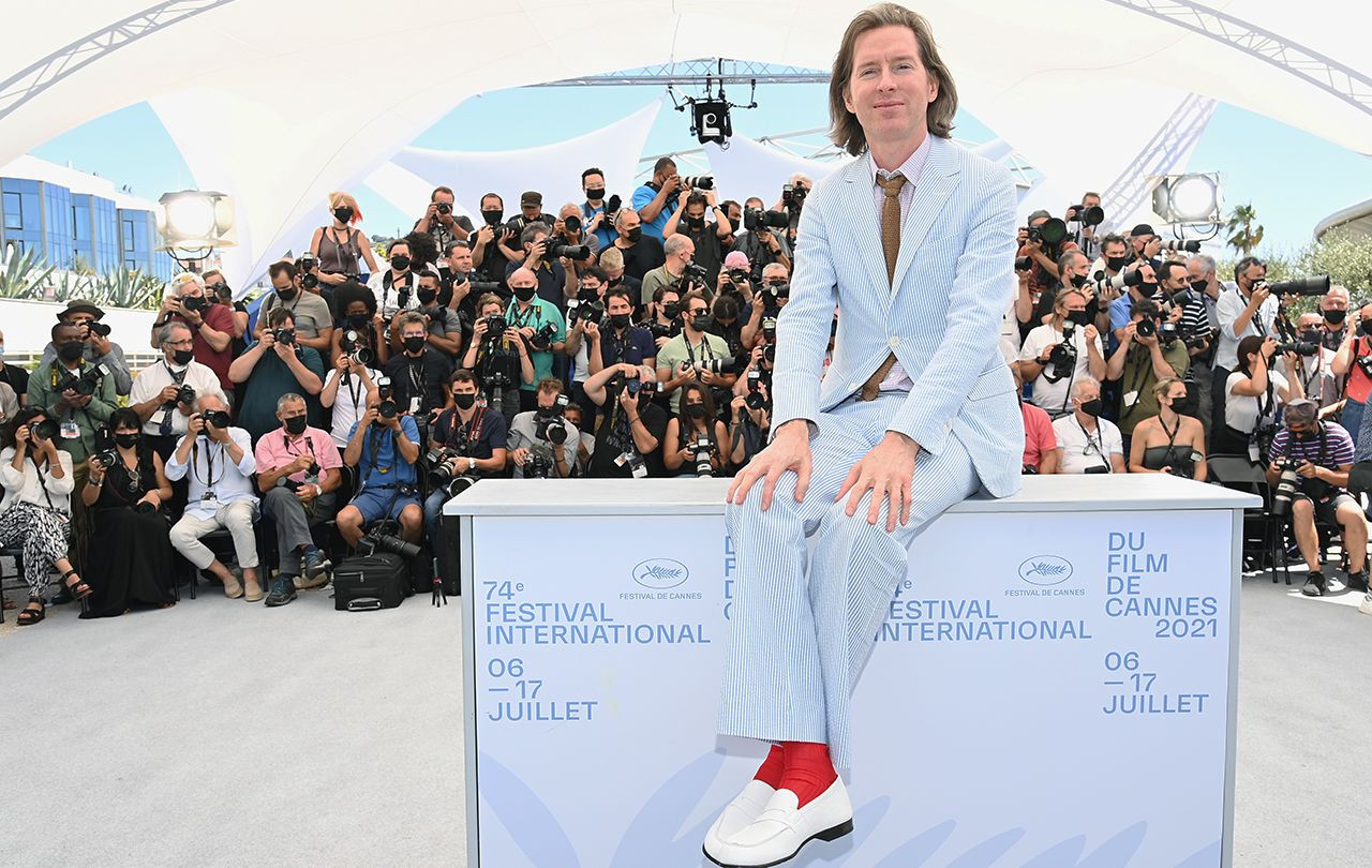 Wes Anderson à Cannes en costume seersucker bleu clair, chaussettes rouges et mocassins blancs.